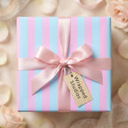 Pastel pink and blue striped baby shower gift wrap with a satin ribbon bow by Wrapped Studios.