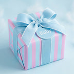 Pink and blue striped baby wrapping paper with a light blue ribbon bow and tag by Wrapped Studios.