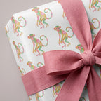 Playful monkey birthday wrapping paper with colorful pastel monkeys and a pink bow, by Wrapped Studios.