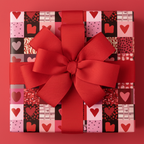 Modern Valentine's Day gift wrap with a patchwork heart pattern in pink, red, and black, tied with a large red grosgrain bow.