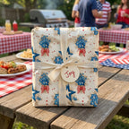Patriotic floral wrapping paper by Wrapped Studios on a gift with cream ribbon at a 4th of July picnic.
