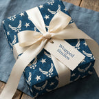 Navy blue Air Force wrapping paper with stars, cream ribbon, and a Wrapped Studios gift tag.