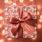 Elegant floral wrapping paper with a dusty rose satin bow, luxury gift wrap by Wrapped Studios.