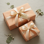 Two blush pink gifts wrapped in solid color wrapping paper with cream satin ribbon and bows.
