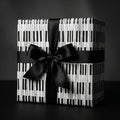 Piano keys wrapping paper on a gift box with a black satin bow, music gift wrap by Wrapped Studios.