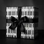 Piano keys wrapping paper on a gift box with a black satin bow, music gift wrap by Wrapped Studios.