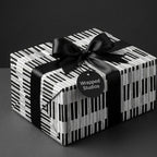 Piano keys music wrapping paper with a black satin ribbon on a gift box by Wrapped Studios.