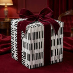 Piano keys music gift wrap with a luxury burgundy velvet bow on a gift box, by Wrapped Studios.