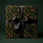 Luxury forest green Christmas wrapping paper with gold trees and a black satin bow by Wrapped Studios.