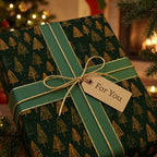 Luxury forest green Christmas wrapping paper with gold trees and ribbon by Wrapped Studios.