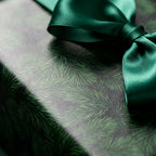 Luxury pine Christmas wrapping paper with an emerald green satin bow by Wrapped Studios.