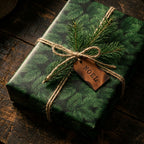 Rustic evergreen Christmas wrapping paper with jute twine and leather Noel tag by Wrapped Studios.