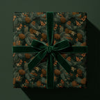 Luxury pinecone holiday wrapping paper with a dark green velvet bow by Wrapped Studios.