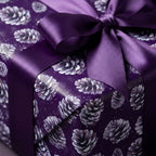 Elegant purple gift wrap with pinecone pattern and matching satin bow.