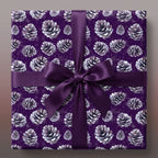 Square gift in purple pinecone Christmas wrapping paper with matching satin ribbon bow.