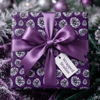 Square Christmas gift wrapped in purple pinecone paper with satin bow by Wrapped Studios.