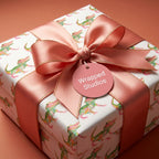 Playful alligator wrapping paper with a coral satin bow and Wrapped Studios gift tag.