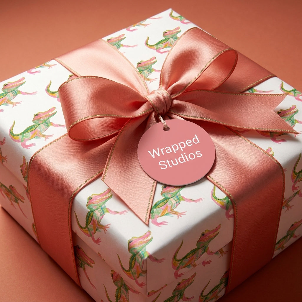 Playful alligator wrapping paper with a coral satin bow and Wrapped Studios gift tag.