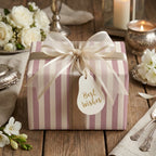 Elegant pink and cream striped wrapping paper with a sheer bow on a wedding table by Wrapped Studios.