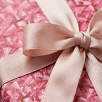 Pink geometric wrapping paper with satin ribbon bow, luxury birthday gift wrap by Wrapped Studios.