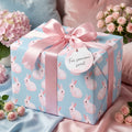 Cute pink and blue bunny wrapping paper on a baby shower gift with a satin bow by Wrapped Studios.
