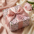 Elegant pink floral wrapping paper with a luxury satin bow by Wrapped Studios, perfect for birthdays.