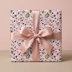 Pink floral wrapping paper with a dusty rose satin ribbon bow on a gift box by Wrapped Studios.