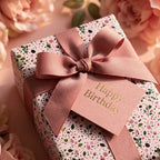 Pink floral birthday wrapping paper with a dusty rose ribbon and tag by Wrapped Studios.