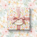 Elegant gift wrapped in peach floral wrapping paper, tied with a satin ribbon and "With Love" tag.