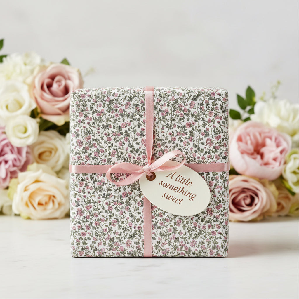 Square gift wrapped in pink floral wrapping paper with a pink ribbon, tag reads "A little something sweet."