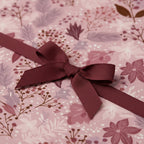 Close-up of pink floral wrapping paper with a burgundy ribbon, perfect for birthday gifts or a unique baby shower present.