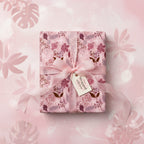 Elegant square gift wrapped in pink floral wrapping paper with a delicate pink ribbon.