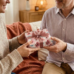 Couple exchanging a gift wrapped in elegant floral wrapping paper with a satin bow. Wrapped Studios.