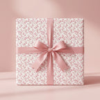 Dainty pink floral wrapping paper with a satin ribbon bow, elegant baby shower gift wrap by Wrapped Studios.