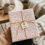 Elegant pink floral wrapping paper with a gold twine bow and gift tag by Wrapped Studios.