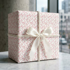 Luxury pink floral wrapping paper with cream satin bow on a gift box, by Wrapped Studios.