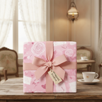 Pink floral romantic wrapping paper with a matching pink bow and "Wrapped Studios" tag, perfect for luxury gifts or a baby shower.