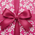 Close-up of a gift wrapped in pink floral wrapping paper with a magenta satin bow.