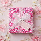 Elegant pink floral wrapping paper with a white ribbon, perfect for birthday gifts or a baby shower.