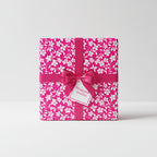 Square gift wrapped in pink floral wrapping paper with a pink ribbon and bow.