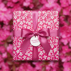 Square gift box in pink floral wrapping paper, tied with a matching pink satin ribbon.