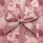 Close-up of a square gift wrapped in blush-toned floral wrapping paper with a silky, matching ribbon and bow.