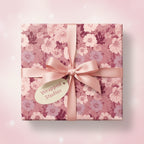 Square gift wrapped in pink floral wrapping paper with a satin ribbon bow.
