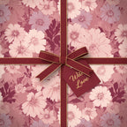 Elegant floral wrapping paper in mauve tones, tied with a burgundy ribbon and "With Love" tag.