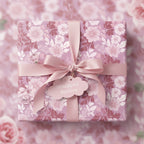 Square gift wrapped in pink floral wrapping paper, tied with a satin ribbon and bow.