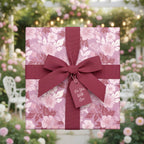 Elegant floral wrapping paper in blush tones with a burgundy ribbon and gift tag against a rose garden backdrop.