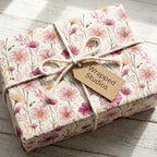 Pink floral wrapping paper with wildflowers and twine on a Wrapped Studios gift box.