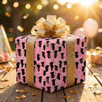 Pink graduation gift wrap with black caps and a glittery gold bow on a gift box by Wrapped Studios.