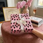 Elegant pink graduation wrapping paper with cap pattern and white ribbon by Wrapped Studios.