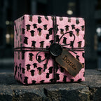 Pink graduation wrapping paper with cap pattern on a gift box with black twine and Done tag by Wrapped Studios.